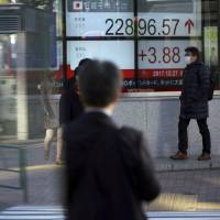 A man walks past an electronic stock board showing the Nikkei 225 index at a securities firm in Tokyo on Wednesday. | AP