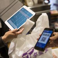 An employee scans a QR code displayed on the Alipay app at a shop in Tokyo. Alipay is working with retailers in popular tourist spots in Japan to make the payment system more widely available. | BLOOMBERG