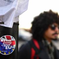 A man walks past a Brexit-related sticker on Westminster Bridge in London on Saturday. | AFP-JIJI