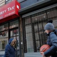 People walk by a Liberty Tax office ahead of Tax Return season in Manhattan, New York, Thursday. | REUTERS