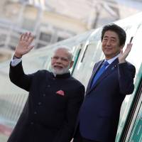 Prime Minister Shinzo Abe and Indian Prime Minister Narendra Modi wave after leaving a shinkansen bullet train during a visit to a plant owned by Kawasaki Heavy Industries Ltd.\'s Rolling Stock Co. in Kobe, Hyogo Prefecture, in November last year. | BLOOMBERG