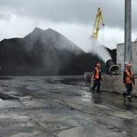 Workers walk past a water cannon spraying water over piles of coal in the Vostochny port area outside the far eastern port of Nakhodka, Russia, Sept. 5. | REUTERS
