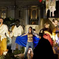 A handout picture taken Sunday and released on Monday by the Femen group shows a police officer running toward a Femen activist standing topless in front of the Nativity scene in Saint Peter\'s square at the Vatican. | FEMEN / VIA AFP-JIJI