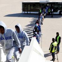 Guinean migrants get on a plane to be deported to Guinea, in Misrata, Libya, Wednesday. | REUTERS