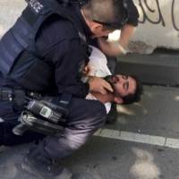 A police officer detains the driver of the car that rammed into pedestrians in Melbourne at Flinders Street Station on Thursday. | SOURCE: TWITTER / @LACHLANVE / VIA REUTERS