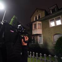 A journalist films a house that has been searched by policemen after they arrested a man planning to carry out a ramming attack in Karlsruhe, Germany, Wednesday. The 29-year-old suspect, a German national, was believed to have scouted the target in the southern German city of Karlsruhe in August and allegedly tried to get a delivery driver job in preparation. | ULI DECK / VIA AFP-JIJI