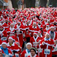People dressed as Santa Claus run through the streets of Michendorf, Germany, Sunday. | REUTERS