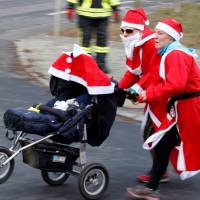 People dressed as Santa Claus run through the streets of Michendorf, Germany, Sunday. | REUTERS