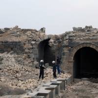 Members of the Civil Defense, also known as the White Helmets, are seen inspecting the damage at a Roman ruin site in Daraa, Syria, Saturday. | REUTERS
