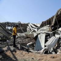 A Yemeni inspects the extent of destruction at a charity\'s food supply storage facility following a reported Saudi-led coalition airstrike in the Yemeni port city of Hodeidah on Dec. 23. | AFP-JIJI