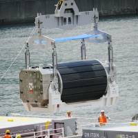 A canister of MOX uranium-plutonium mixed oxide fuel is unloaded from a transport vessel at Kansai Electric Power Co.\'s Takahama nuclear plant in Fukui Prefecture in June 2010. | KYODO