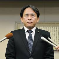 Kaga Municipal Assembly member Hiroto Inui speaks to reporters at the Kaga Municipal Government building in Ishikawa Prefecture last week about his anonymous online slandering of a local restaurant. | KYODO