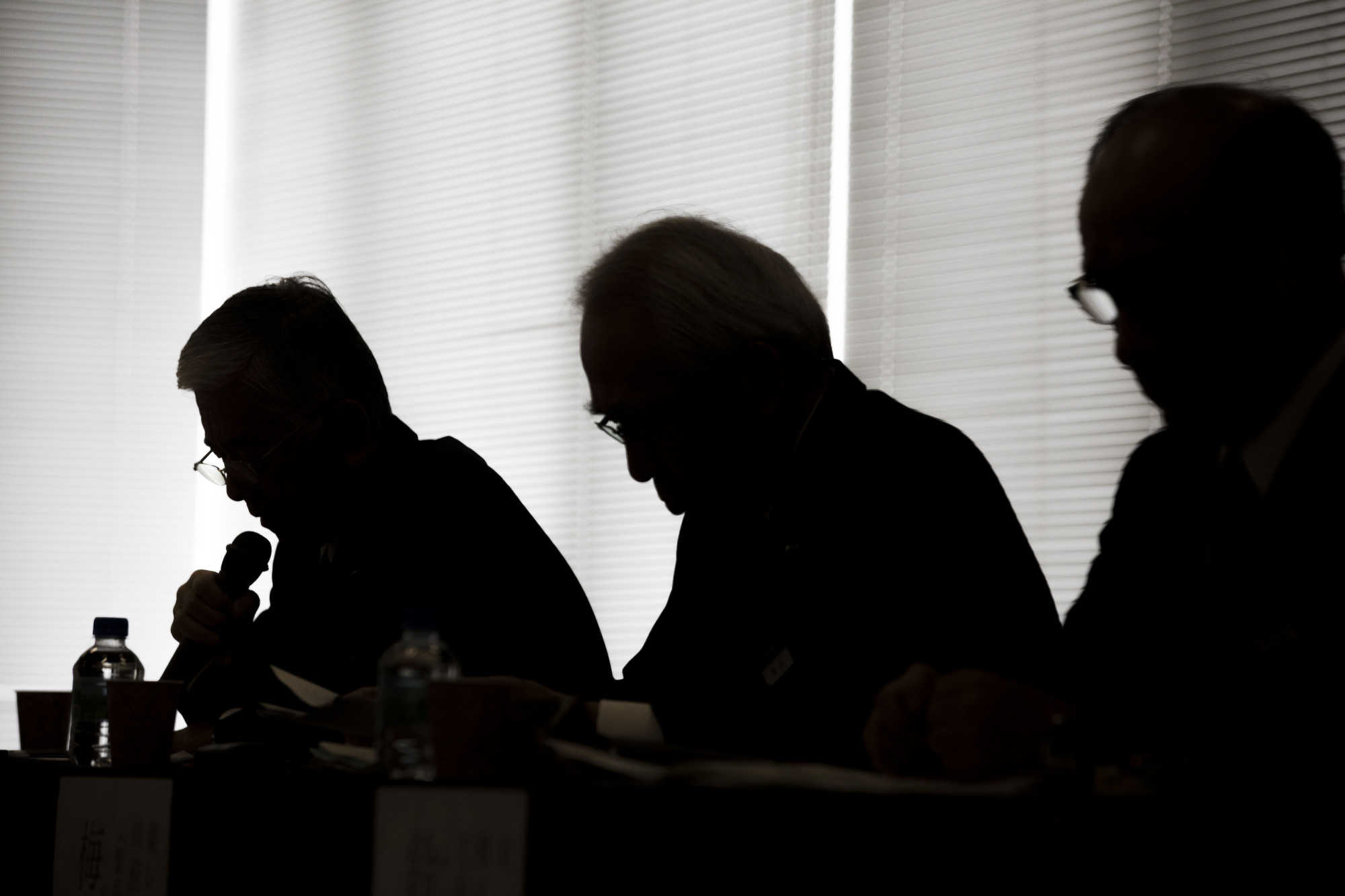 Shadowy figures: The silhouettes of Toray Industries President Akihiro Nikkaku (left), Executive Vice President Akira Umeda (center) and Nobuhiro Suzuki, president of Toray Hybrid Cord Inc., a Toray unit that makes cords that go into tires, are seen as they attend a news conference in November. | BLOOMBERG