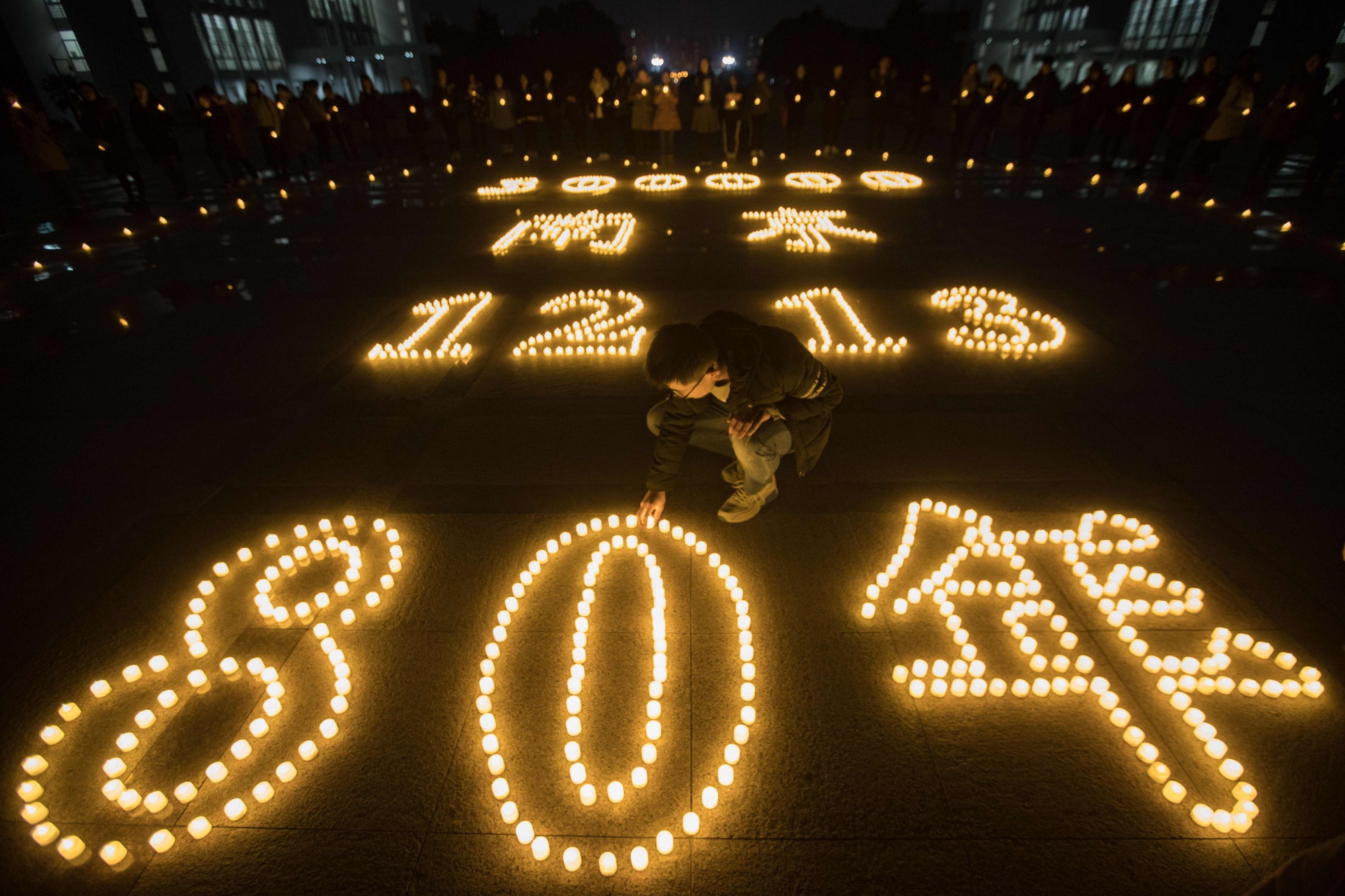 Students light candles at Nanjing Normal University on Dec. 11 during a ceremony ahead of China's Dec. 13 National Memorial Day for Nanjing massacre victims in Nanjing. | AFP-JIJI