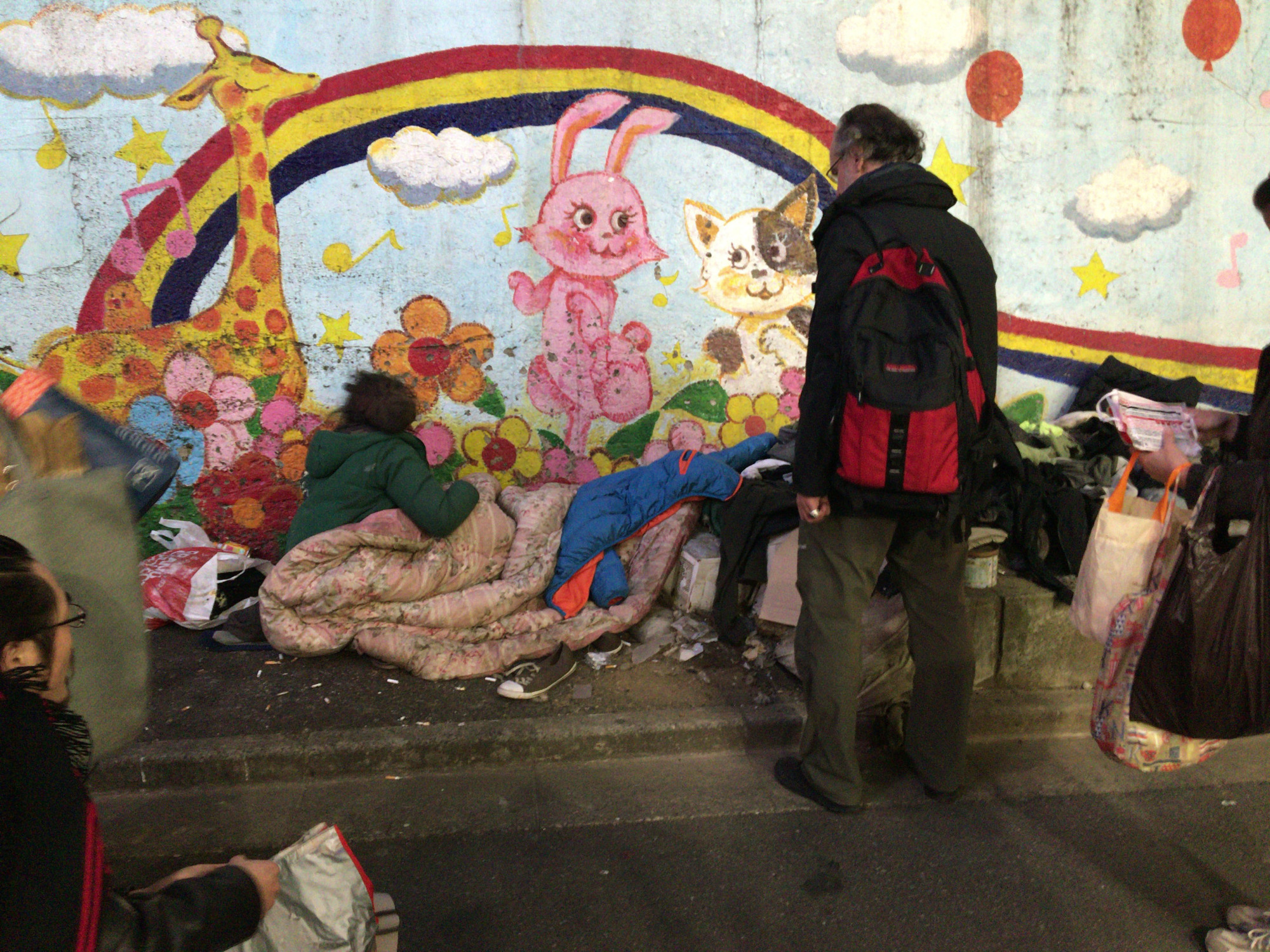 Study in contrasts: A homeless man sleeps next to a mural in Tokyo's Shinjuku district. | SIMON SCOTT
