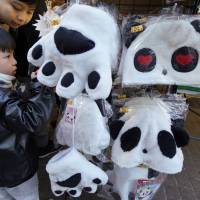 Children look at panda goods at an open-air market in the Ameyoko shopping district near Ueno Zoo in Tokyo on Dec. 17. | AP