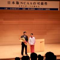Former education minister and pro wrestler Hiroshi Hase (left) stands with gymnast Kenzo Shirai during a symposium on the creation of a Japanese version of the NCAA on Saturday at Nippon Sport Science University. | KAZ NAGATSUKA