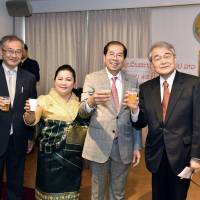 Laotian Ambassador Viroth Sundara (second from right) and his wife, Simuang, pose for a photo with Fumio Shimizu (left), deputy director-general of the Asian and Oceanian Affairs Bureau, and Itsuo Hashimoto, president of the Japan-Laos Association, at a celebration to mark Laos\' national day at the Laotian Embassy on Dec. 3. | YOSHIAKI MIURA