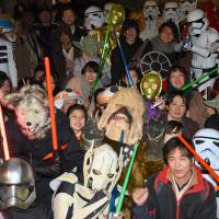Some of the nearly thousand \"Star Wars\" fans &#8212; many dressed as their favorite heroes and villains from the film franchise &#8212;  wait in excitement outside Toho Cinemas\' Roppongi theater in Tokyo\'s Minato Ward for the Japanese premiere of \"The Last Jedi\" on Thursday. | SATOKO KAWASAKI