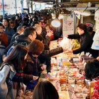 People crowd a stall at the Tsukiji fish market in Tokyo\'s Chuo Ward on Friday to buy food for the New Year\'s holidays. The market, famed for its early morning tuna auctions, is scheduled move to its controversial new home in the Toyosu waterfront area on Oct. 11. | YOSHIAKI MIURA