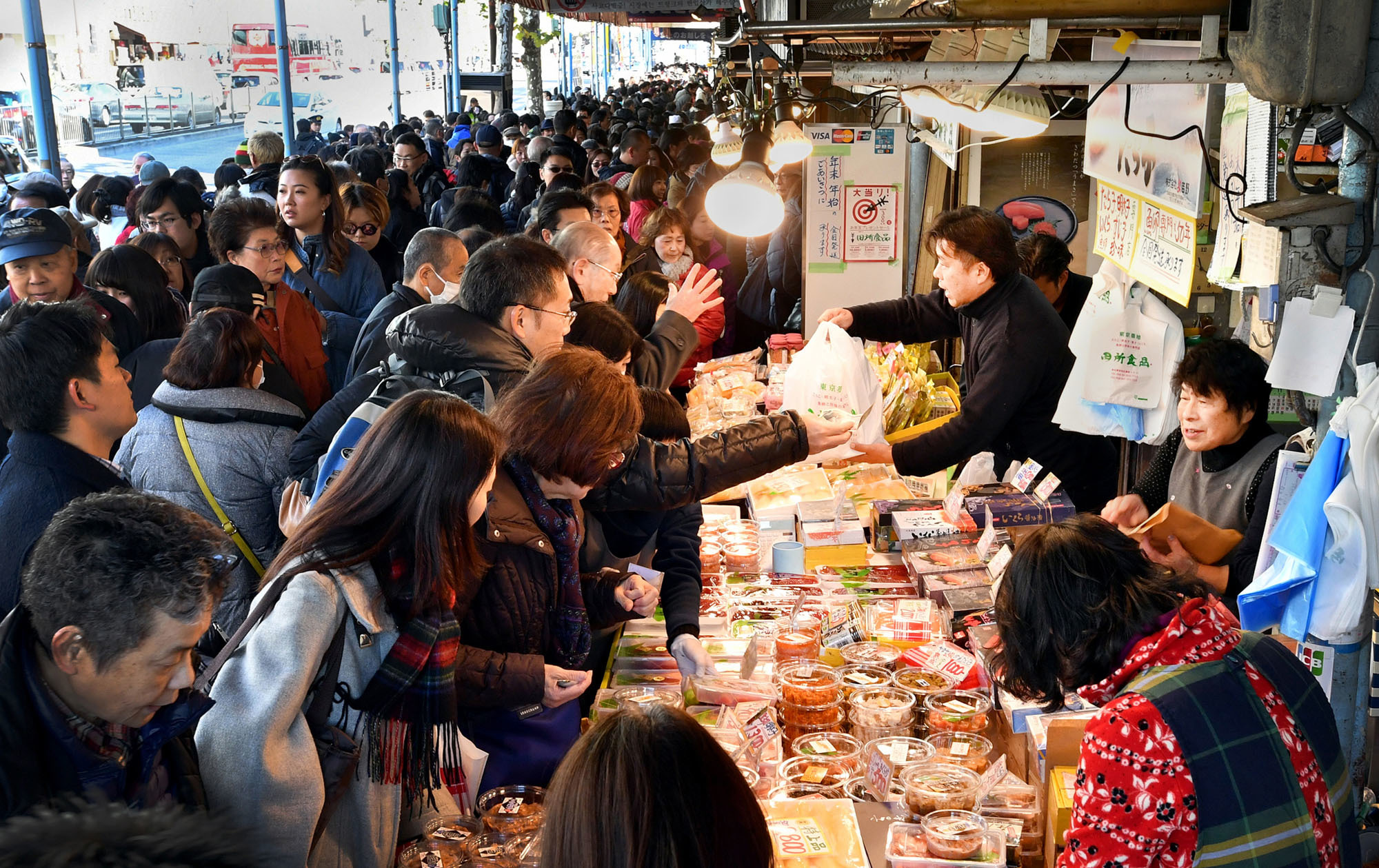 People crowd a stall at the Tsukiji fish market in Tokyo's Chuo Ward on Friday to buy food for the New Year's holidays. The market, famed for its early morning tuna auctions, is scheduled move to its controversial new home in the Toyosu waterfront area on Oct. 11. | YOSHIAKI MIURA