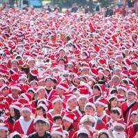 Some 5,500 people dressed as Santa Claus participate in a walking event Sunday at Osaka Castle Park in the city of Osaka. A portion of the fees paid to join the event will be used to buy Christmas gifts for children in hospitals, the organizer said. | OSAKA GREAT SANTA RUN