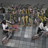 Cyclists try to park Mobike bicycles on a crowded street in Shanghai. | BLOOMBERG