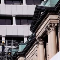 Men work on the outside of the Bank of Japan building in Tokyo earlier this week. | REUTERS