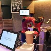 A robotic arm holds a paper cup at a cafe in Tokyo\'s Shibuya Ward on Tuesday. | KYODO