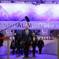 Followed by a television team and assistants, Klaus Schwab, founder and executive chairman of the World Economic Forum, walks through the meeting\'s conference center in Davos, Switzerland, Sunday. The meeting brings together entrepreneurs, scientists, chief executives and political leaders from Tuesday to Jan. 26. | AP