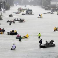 Rescue boats float on a flooded street as people are evacuated from rising floodwaters brought on by Tropical Storm Harvey in Houston last August. The National Hurricane Center\'s official report on Harvey compiles staggering numbers, starting with 68 dead and &#36;125 billion in damage. But the really big numbers in the Thursday tally have to do with the rainfall that swamped Houston. Two places had more than 5 feet of rain. | AP