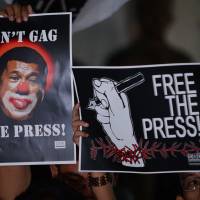 Journalists and supporters display placards depicting Philippine President Rodrigo Duterte as a clown during a protest backing press freedoms in Manila on Friday. | AFP-JIJI