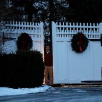 A man is seen at the gate to the home of former U.S. President Bill Clinton and former Democratic presidential candidate Hillary Clinton after firefighters were called to put out a fire at the property in Chappaqua, New York, Wednesday. | REUTERS
