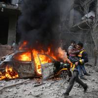 A Syria Civil Defense member carries a wounded child in the besieged town of Hamoria, eastern Ghouta, in Damascus Saturday. | REUTERS