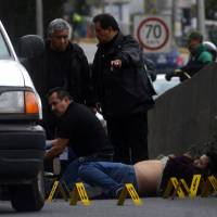 Forensic technicians stand at a crime scene where a man was killed by unknown assailants in Xalapa, Mexico, Saturday. | REUTERS