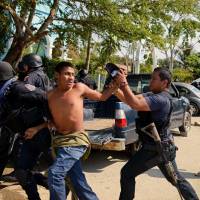 A member of the Regional Coordinator of Community Authorities (CRAC) is arrested by Guerrero state policemen after a series of clashes that left at least 11 people dead at La Concepcion village, Acapulco municipality, in Guerrero state, Mexico, Sunday. | AFP-JIJI