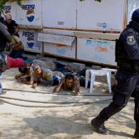 Guerrero policemen are seen during the arrest of a member of the Regional Coordinator of Community Authorities (CRAC) after a series of clashes that left at least 11 people dead at La Concepcion village, Acapulco municipality, in Guerrero state, Mexico, Sunday. | AFP-JIJI