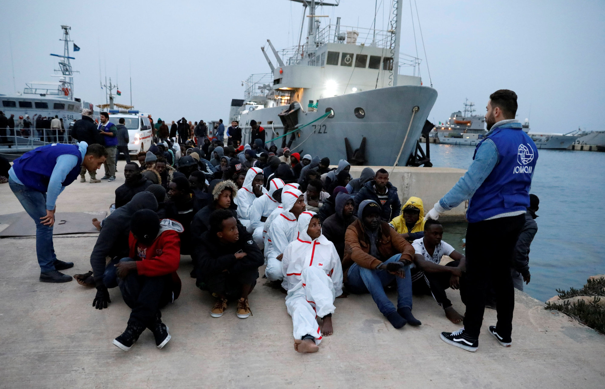 Migrants sit at a naval base after they were rescued by Libyan coast guard boats, in Tripoli Tuesday. | REUTERS