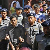 Myanmar police officers escort detained Reuters journalists Kyaw Soe Oo (second from left) and Wa Lone (fourth from left in back row) from a court after a hearing in Yangon, Myanmar, on Tuesday. | AP