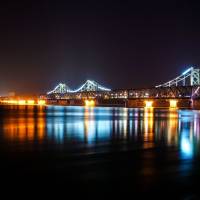 Spotlight beams are seen from the North Korean town of Sinuiju, past the Friendship Bridge and Broken Bridge, as seen from Dandong, in China\'s northeastern Liaoning province, on Wednesday. | AFP-JIJI