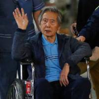 Former Peruvian President Alberto Fujimori waves to supporters as he is wheeled out of the Centenario Clinic in Lima, where he was hospitalized, on Jan. 4 after receiving a Christmas Eve pardon from President Pedro Pablo Kuczynski. | AFP-JIJI