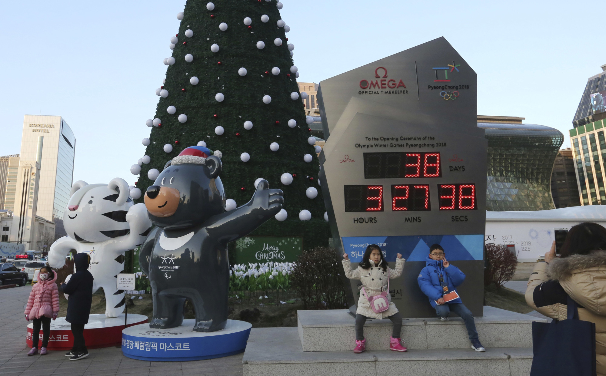 Children pose Tuesday in Seoul in front of an electric board that shows the number of days left until the opening of the Pyeongchang Winter Olympic Games and beside the official mascots, the white tiger Soohorang for the Olympics and the black bear Bandabi for the Paralympics. | AP