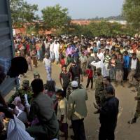 Rohingya refugees watch as others receive relief material at the Kutupalong refugee camp near Cox\'s Bazar, Bangladesh, Tuesday. Bangladesh and Myanmar have agreed that they will try to complete the repatriation of hundreds of thousands of Rohingya Muslim refugees who fled from violence in Myanmar within two years, Bangladesh\'s Foreign Ministry said Tuesday. | AP