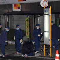Police investigate a scene where multiple stabbings took place in the city of Hiroshima. A 33-year-old man was arrested early Monday on suspicion of attacking two men on a street, killing one of them. | KYODO