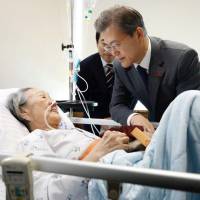 S. Korean President Moon Jae-in is seen with former \"comfort woman\" Kim Bok-dong at a hospital in Seoul on Thursday in this government released photo. | REUTERS