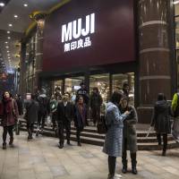 Shoppers walk past a Muji store, operated by Ryohin Keikaku Co., in Shanghai in December 2015. | BLOOMBERG