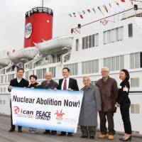 Hibakusha from Hiroshima and Nagasaki pose Monday with others in Yokohama in front of a ship chartered by Peace Boat. | KYODO