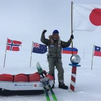Adventurer Yasunaga Ogita holds up a Japanese flag at the South Pole Friday after walking 1,126 km alone &#8212; without extra supplies &#8212; from a coastal area of Antarctica, becoming the first Japanese to achieve the feat. | YASUNAGA OGITA