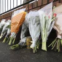 Flowers and a can of Japanese coffee are placed on Avenue Road in Dundalk, Ireland, Thursday close to the scene of a murdered Japanese man. | NIALL CARSON / PA / VIA AP