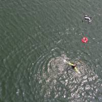 Officials from the Yaizu Crisis Management Division guide a drone that has been fitted with a life buoy to the location of a person in need of help in the ocean as part of an emergency drill. | COURTESY OF YAIZU CITY CRISIS MANAGEMENT DIVISION